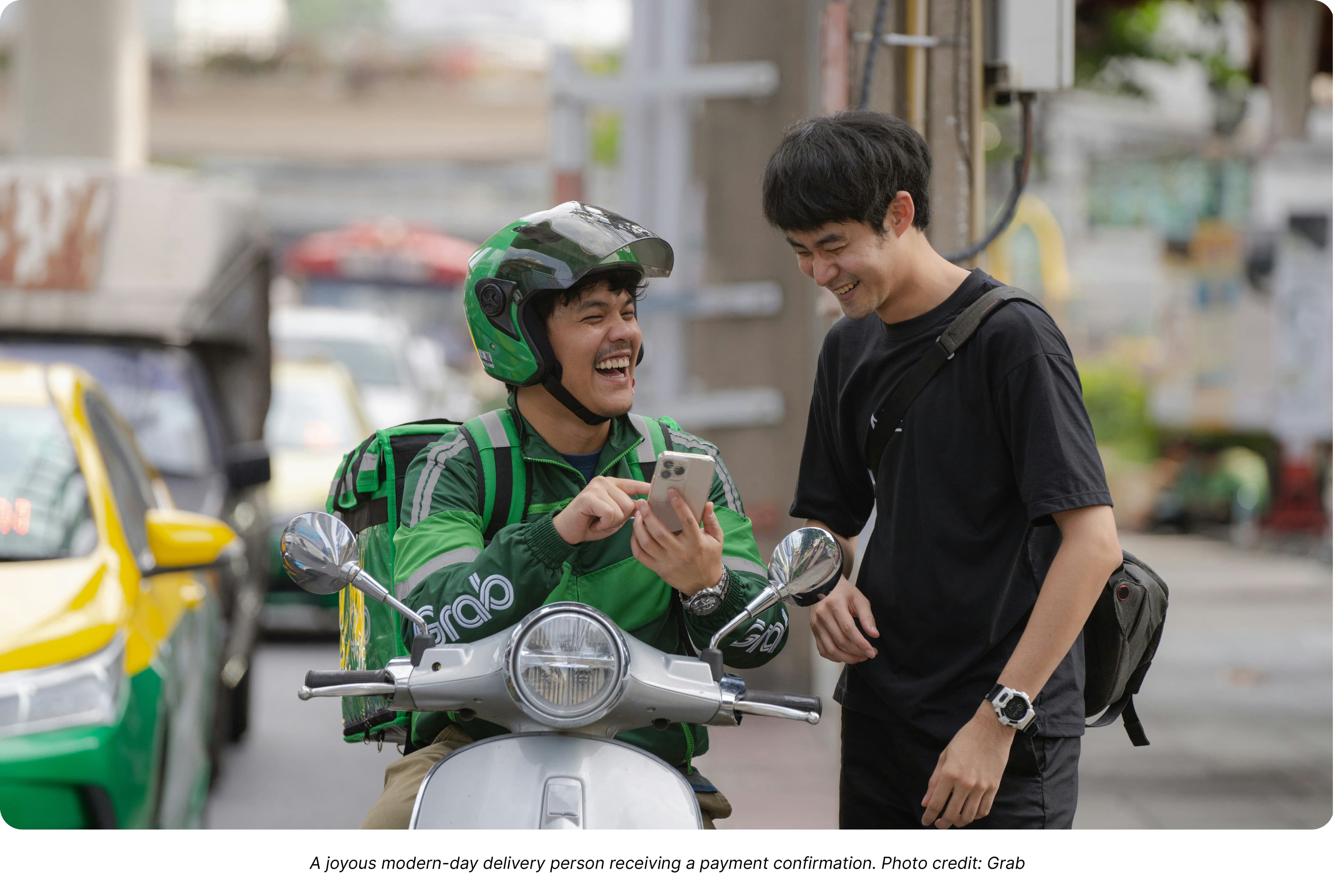 A joyous modern-day delivery person receiving a payment confirmation. Photo credit: Grab
